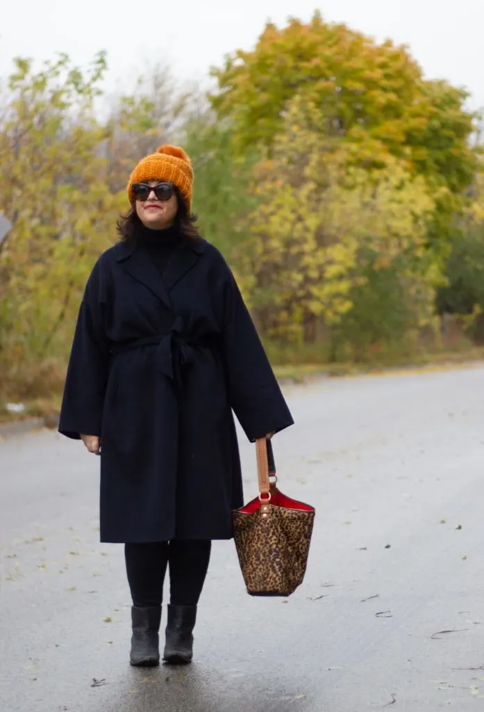 navy wrap coat, black turtleneck, burnt orange hat, leopard bag.